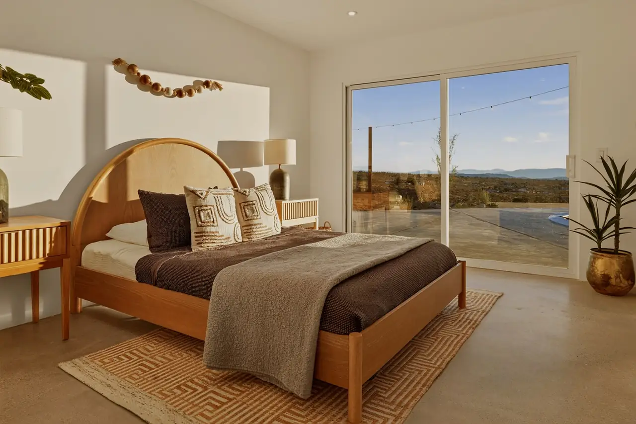 Guest bedroom with arched wood headboard and desert view