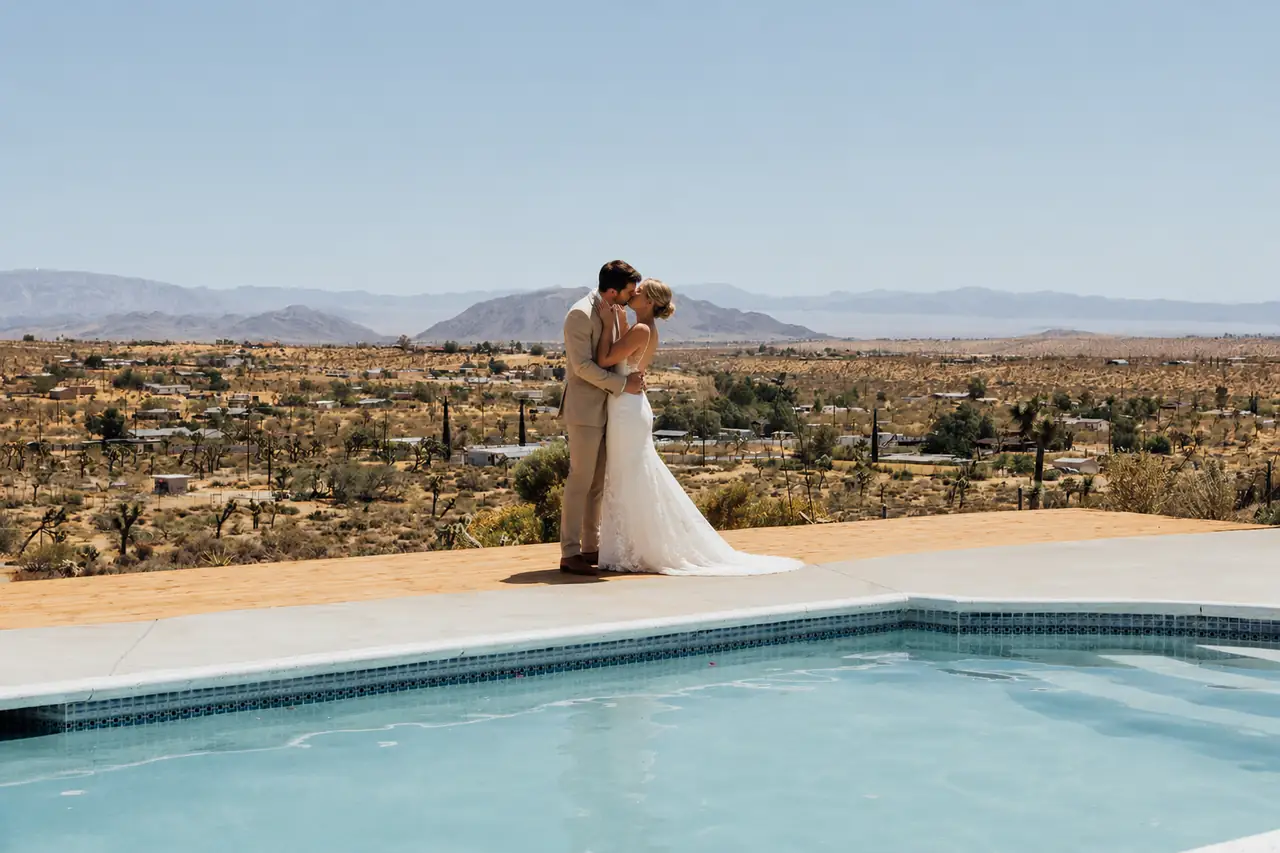 Bride and groom embracing poolside with desert vista